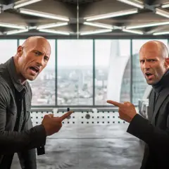 Dwayne Johnson i Jason Statham, czyli szybcy i wściekli: hobbs i shaw obsada, wskazują na siebie z groźną miną w biurowcu.