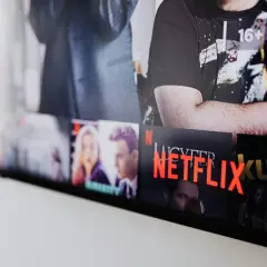 Ekran telewizora z widocznymi okładkami filmów i seriali. Widać napis "NETFLIX" i polskie nowości.