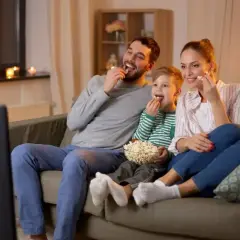 Rodzina z synem zajada popcorn, oglądając filmy dla dzieci.