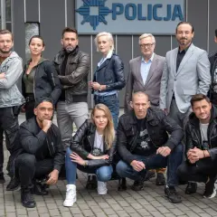 Cała gliniarze obsada pozuje przed budynkiem policji.