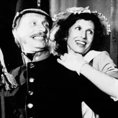 Uśmiechnięta para z filmu "C.K. Dezerterzy" - mężczyzna w mundurze i kobieta w kapeluszu.