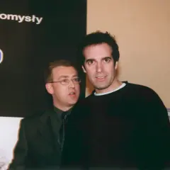 David Copperfield, w czarnym swetrze, stoi obok mężczyzny w garniturze.