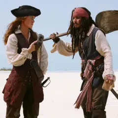 Elizabeth Swann i Kapitan Jack Sparrow, bohaterowie filmów "Piraci z Karaibów", stoją na piaszczystej plaży.