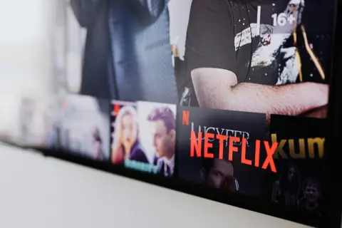 Ekran telewizora z widocznymi okładkami filmów i seriali. Widać napis "NETFLIX" i polskie nowości.