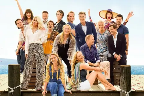 Mamma Mia: Here We Go Again! obsada. Uśmiechnięci aktorzy na tle błękitnego nieba i morza.