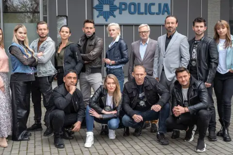 Cała gliniarze obsada pozuje przed budynkiem policji.