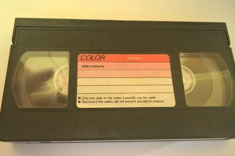 Czarna kaseta wideo z etykietą "COLOR videocassette". Widać dwie rolki taśmy.