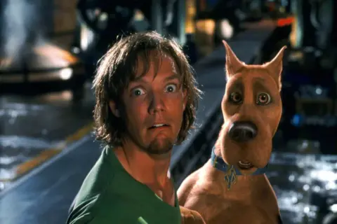 Przerażeni Shaggy i Scooby-Doo wpadają na siebie, gdy uciekają przed potworem.