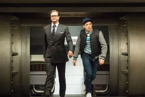 Colin Firth i Taron Egerton, czyli gwiazdy Kingsman: Tajne Służby, wychodzą zza masywnych drzwi.