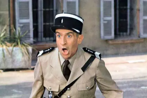 Louis de Funès w filmach, w mundurze żandarma, z miną pełną zdziwienia i rozbawienia.