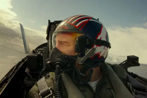 Pilot w kasku z flagą USA, gotowy do akcji w kokpicie myśliwca. Czy to zapowiedź Top Gun 3?