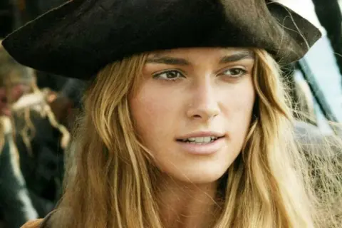Elizabeth Swann z obsady "Piraci z Karaibów" w pirackim kapeluszu, z rozwianymi blond włosami.