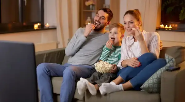 Rodzina z synem zajada popcorn, oglądając filmy dla dzieci.