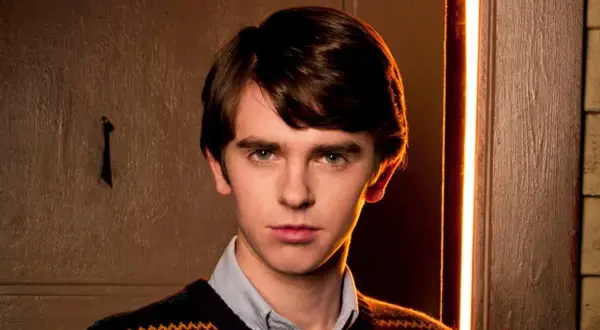 Freddie Highmore w swetrze i koszuli, zamyślony. Jego filmy, seriale i programy często poruszają złożone tematy.