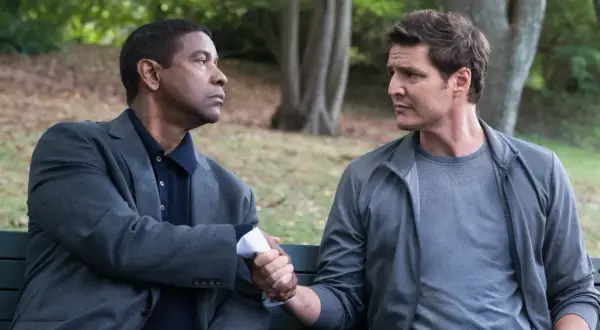 Denzel Washington i Pedro Pascal, obsada "Bez litości 2", ściskają sobie dłonie na ławce w parku.
