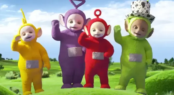 Tinky Winky, Dipsy, Laa-Laa i Po – teletubisie imiona znane dzieciom. Wesołe postacie machają do widzów na zielonej łące.