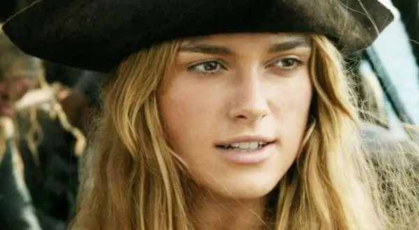 Elizabeth Swann z obsady "Piraci z Karaibów" w pirackim kapeluszu, z rozwianymi blond włosami.