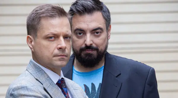 Dwóch mężczyzn, twórcy filmu braci Sekielskich, patrzy w obiektyw. Jeden w garniturze, drugi w marynarce i t-shircie.