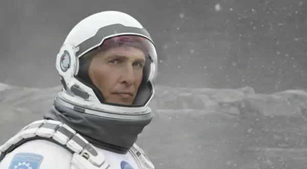 Astronaut Cooper z filmu Interstellar 2 w skafandrze kosmicznym, na tle zamarzniętego krajobrazu.