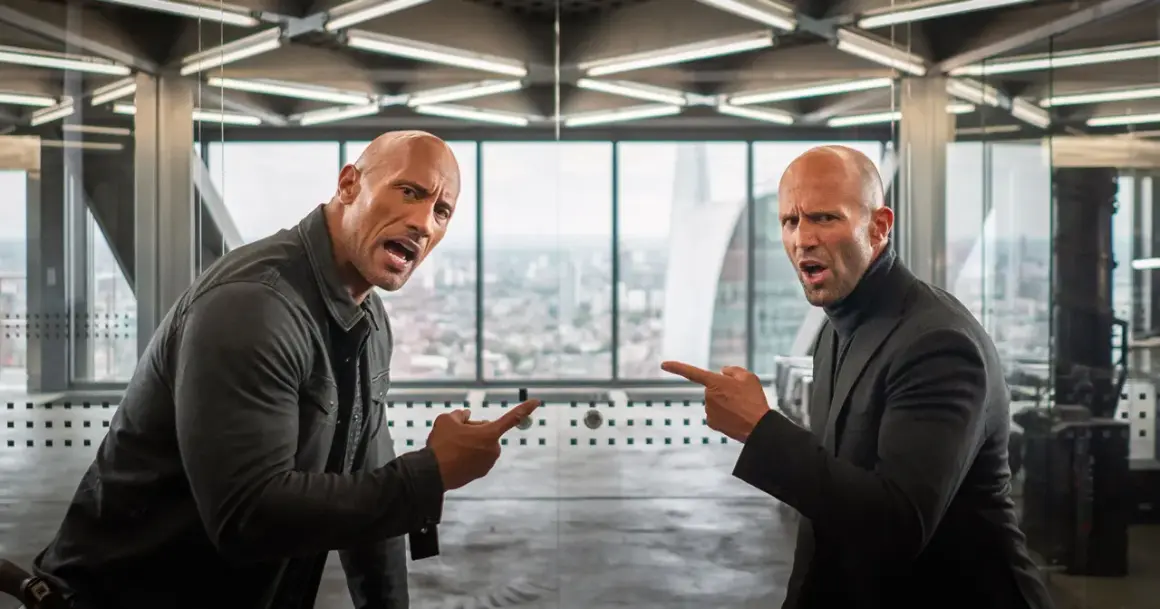 Dwayne Johnson i Jason Statham, czyli szybcy i wściekli: hobbs i shaw obsada, wskazują na siebie z groźną miną w biurowcu.