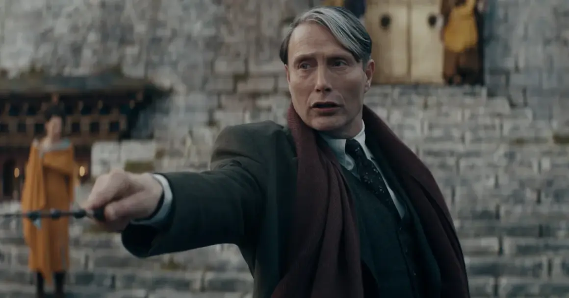 Mads Mikkelsen w roli Grindelwalda, z różdżką w dłoni, w filmie z serii "Fantastyczne zwierzęta".