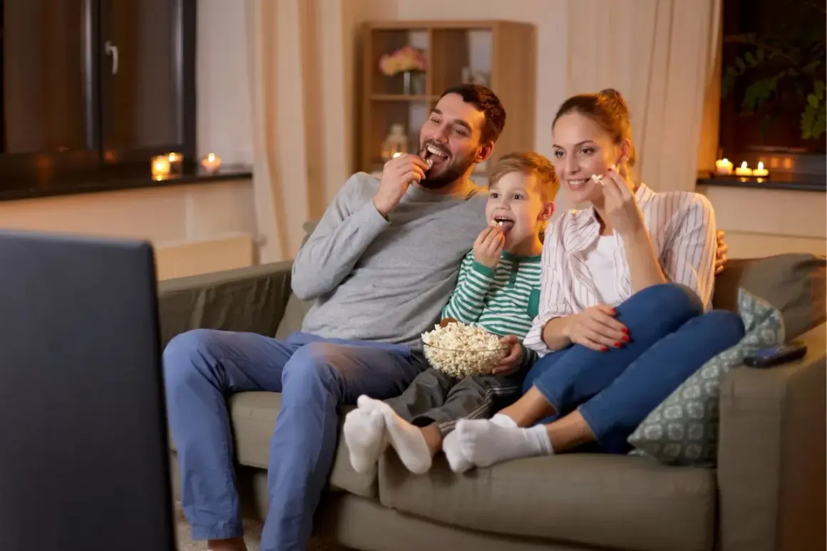 Rodzina zajada popcorn podczas oglądania filmów familijnych.