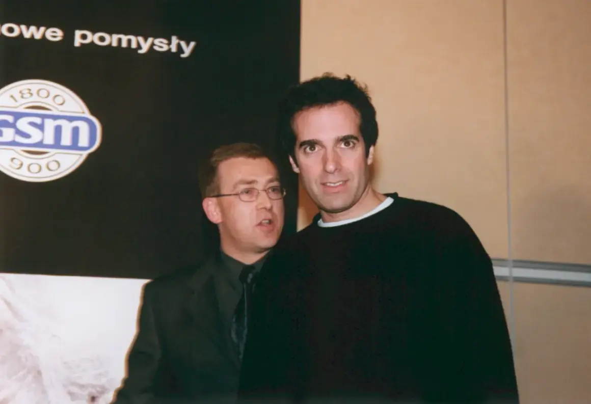 David Copperfield, w czarnym swetrze, stoi obok mężczyzny w garniturze.
