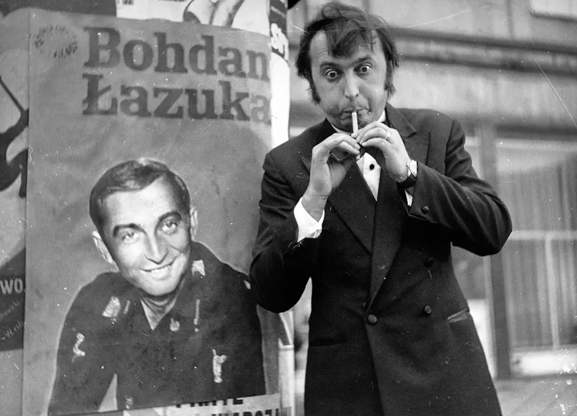 Bohdan Łazuka z papierosem w ustach, obok plakat z jego podobizną. To chyba nie jest jego ulubiony dzień, ale obsada "Nie lubię poniedziałku" na pewno się cieszy.