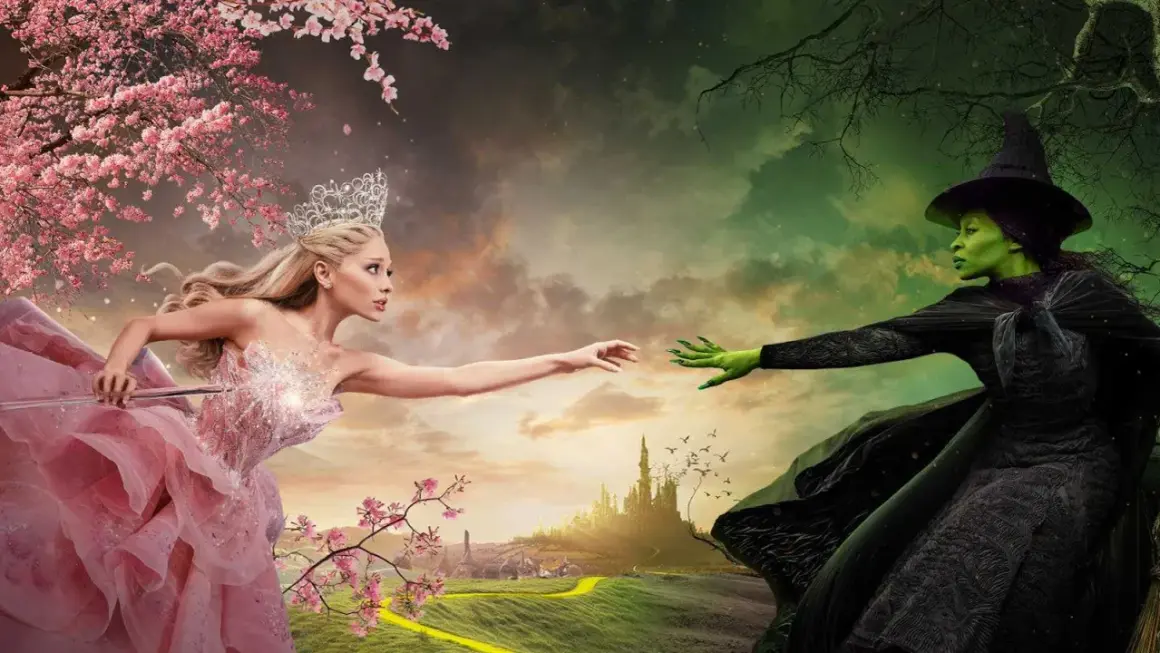 Królowa w różowej sukni i zielona wiedźma z "Wicked 2" wyciągają do siebie ręce na tle baśniowego krajobrazu.