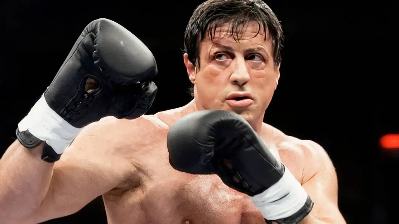 Sylvester Stallone jako Rocky Balboa w 7. części sagi, zacięty w walce, z rękawicami bokserskimi i śladami potu.