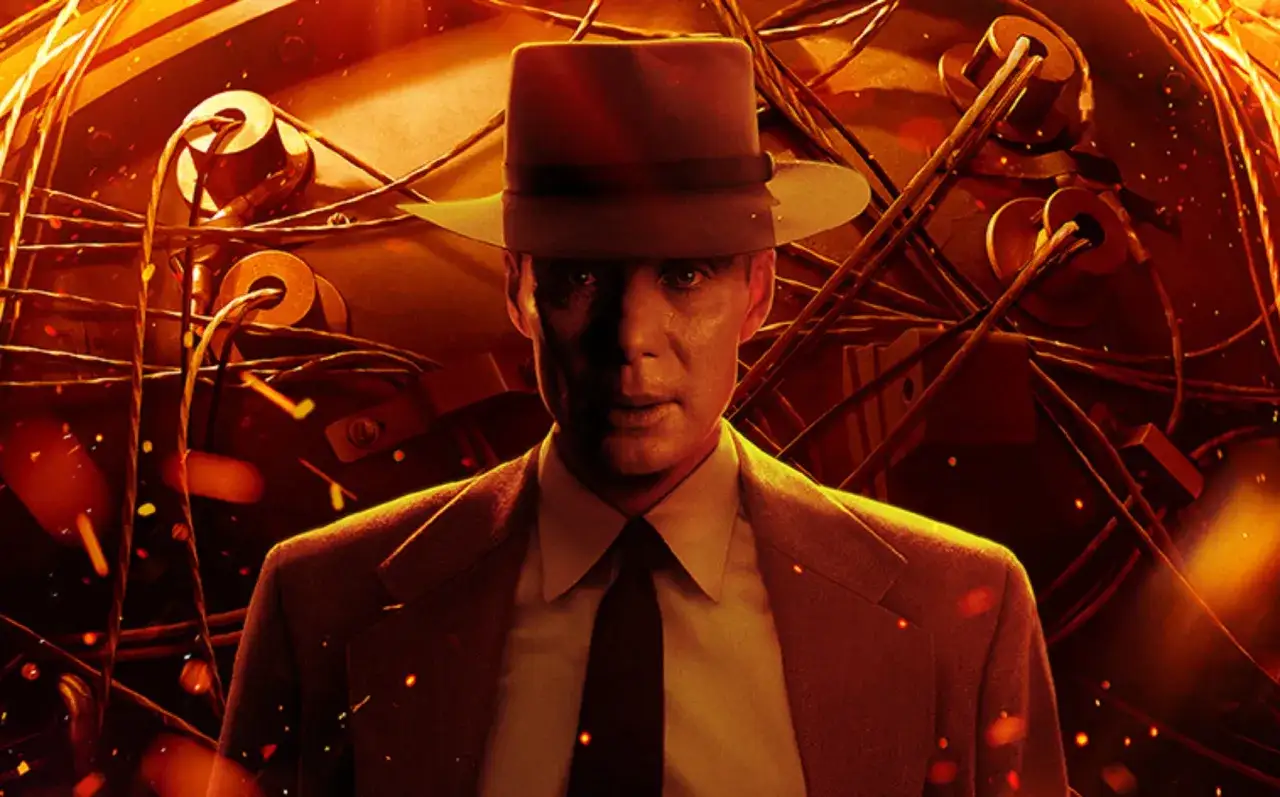 Cillian Murphy jako Oppenheimer w kapeluszu i garniturze, otoczony skomplikowaną maszynerią i płomieniami.