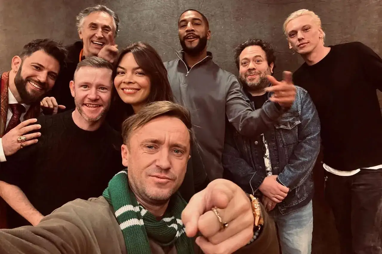 Uśmiechnięta obsada Harry'ego Pottera, w tym Tom Felton, Jamie Campbell Bower i inni, pozuje do wspólnego zdjęcia.