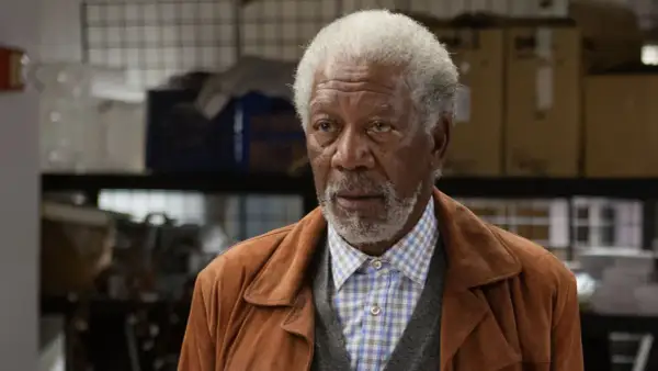 Morgan Freeman w brązowej kurtce i kratowanej koszuli, jak z jego filmów.
