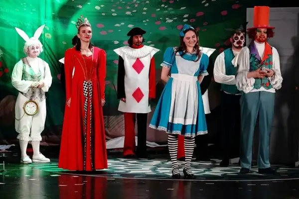 Alicja w Krainie Czarów postacie: Biały Królik z zegarem, Królowa Kier, Walet Kier, Alicja, Szalony Kapelusznik i inni na scenie.