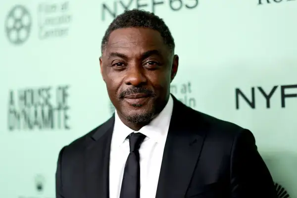 Idris Elba, znany z filmów, seriali i programów, w czarnym garniturze i krawacie.