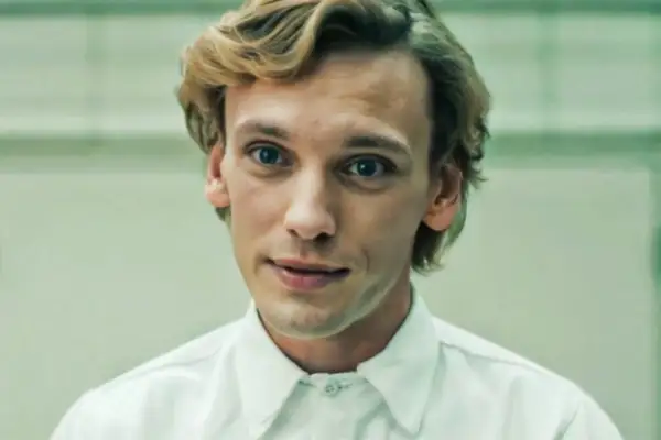 Jamie Campbell Bower, aktor wcielający się w postać Vecny, z niebieskimi oczami i blond włosami, w białej koszuli.
