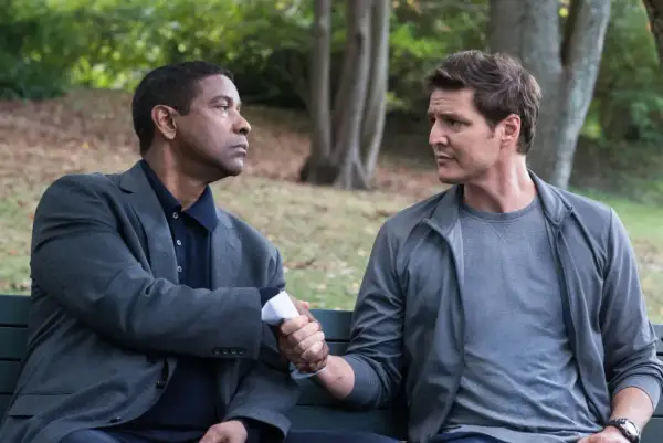 Denzel Washington i Pedro Pascal, obsada "Bez litości 2", ściskają sobie dłonie na ławce w parku.