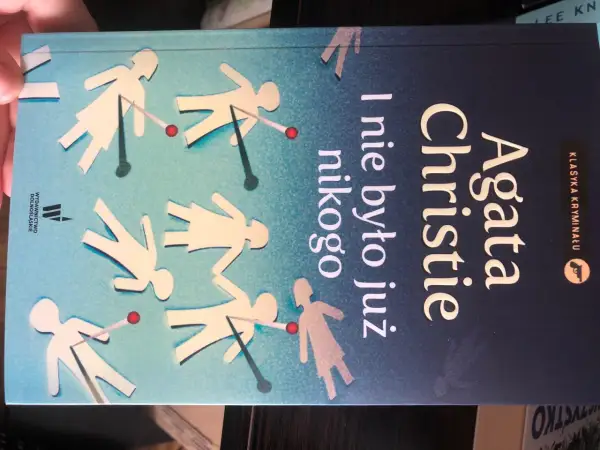 Okładka książki Agaty Christie "I nie było już nikogo" z sylwetkami ludzi przeszywanymi szpilkami.