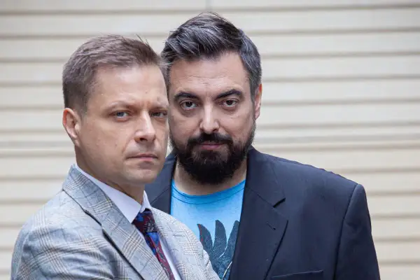 Dwóch mężczyzn, twórcy filmu braci Sekielskich, patrzy w obiektyw. Jeden w garniturze, drugi w marynarce i t-shircie.