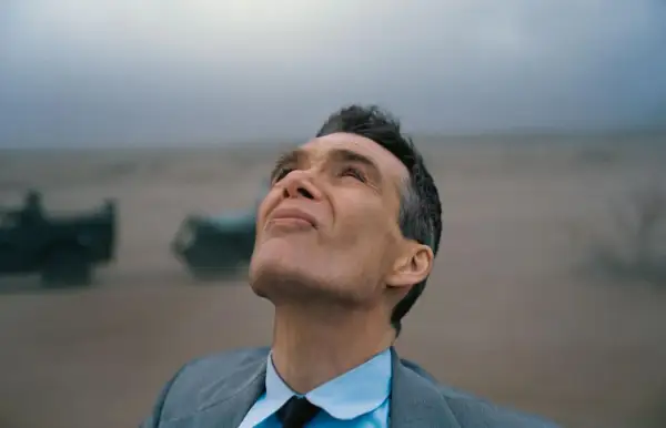 Oppenheimer patrzy w niebo, w tle mglisty krajobraz z pojazdami.