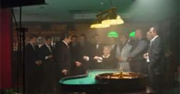 Wielki Szu obsada w kasynie, przy stole do ruletki. Mężczyźni w garniturach obserwują grę.